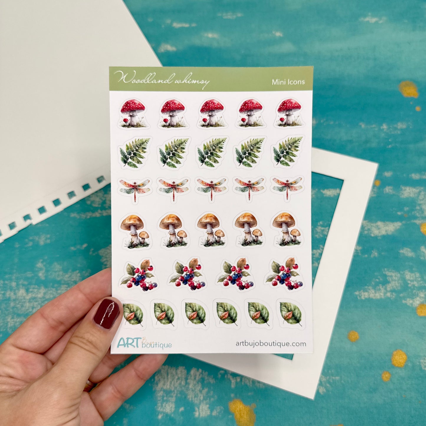 Sheet of nature-themed stickers held by a hand on a textured blue background