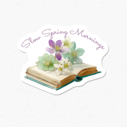 Decorative card with flowers on an open book, text 'Slow Spring Mornings', on a light background.