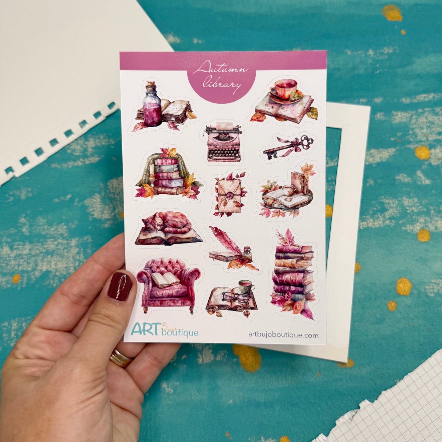Sheet of decorative stickers with 'Autumn Library' theme held by a hand on a textured surface.