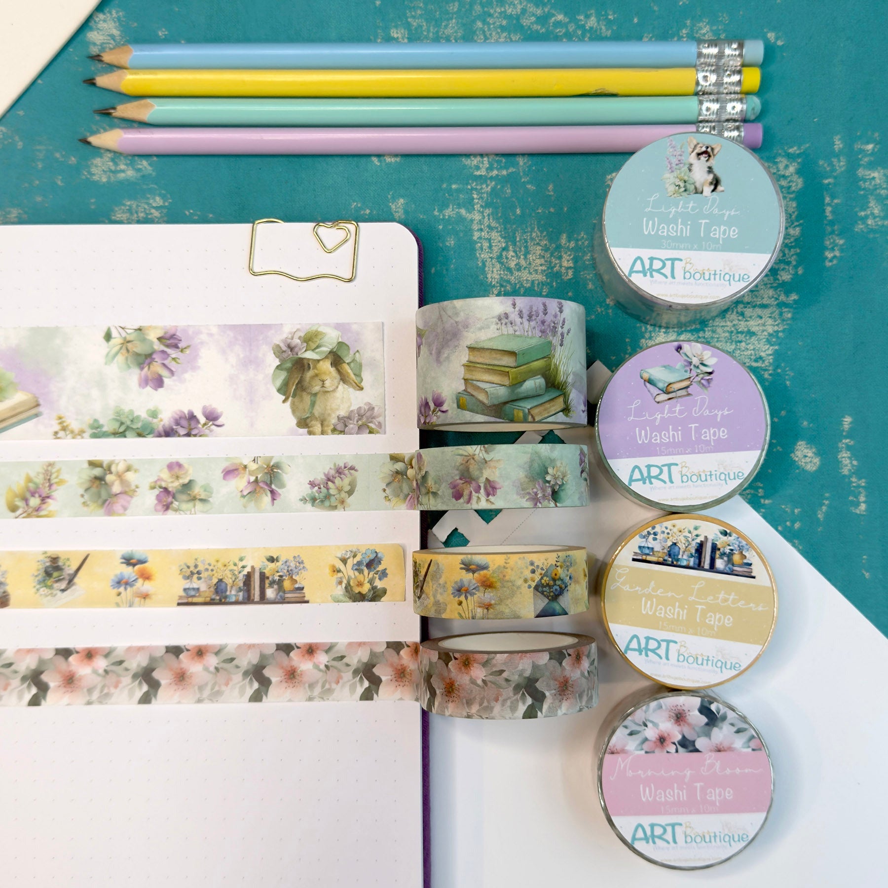 Stationery items including pencils, washi tape, and a notebook on a textured surface.