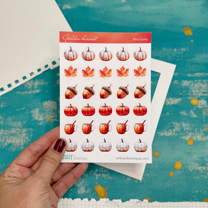 Sheet of autumn-themed stickers held by a hand on a textured blue background