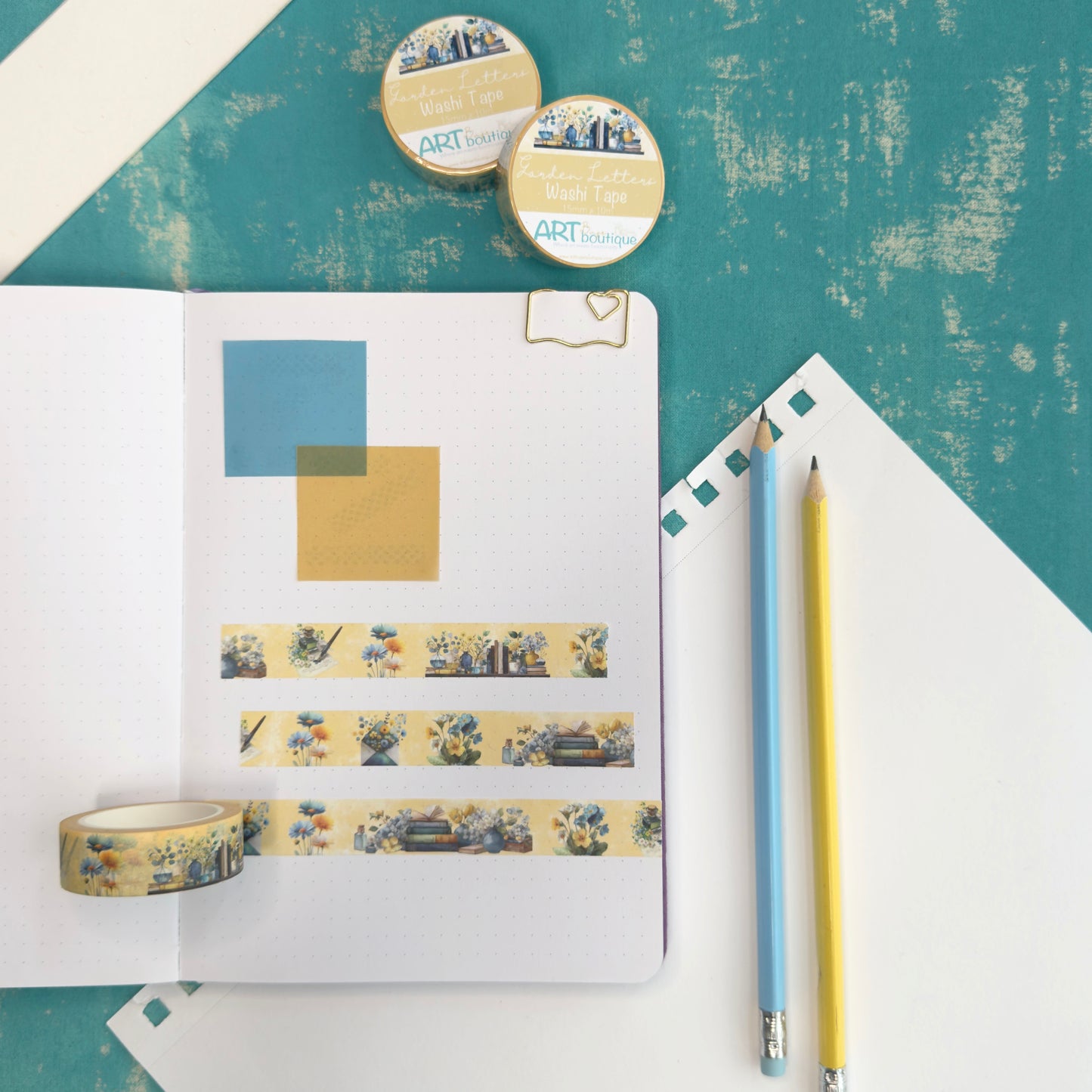 Notebook with washi tape, pencils, and decorative items on a textured surface