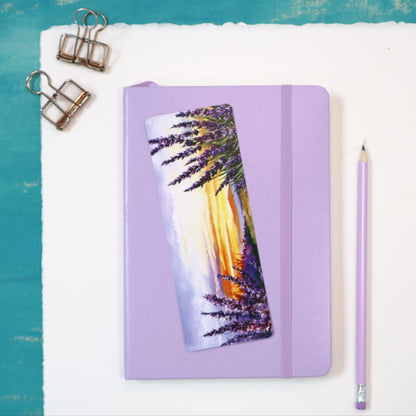 Purple notebook with a scenic bookmark on a white surface with a teal border.
