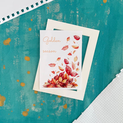 Greeting card with autumn leaves design on a textured teal background