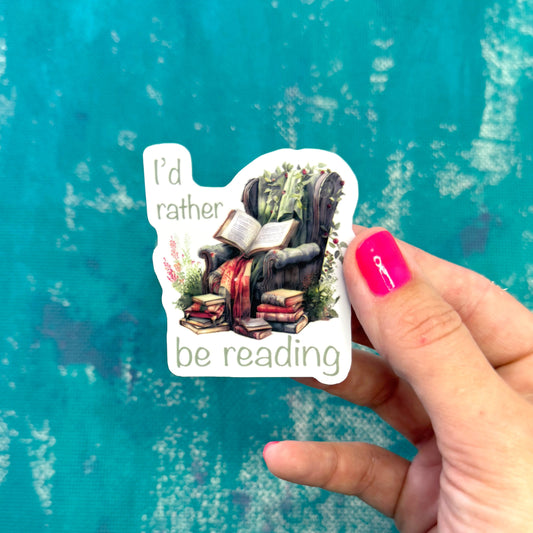 Sticker with a reading-themed design held by a hand against a textured blue background