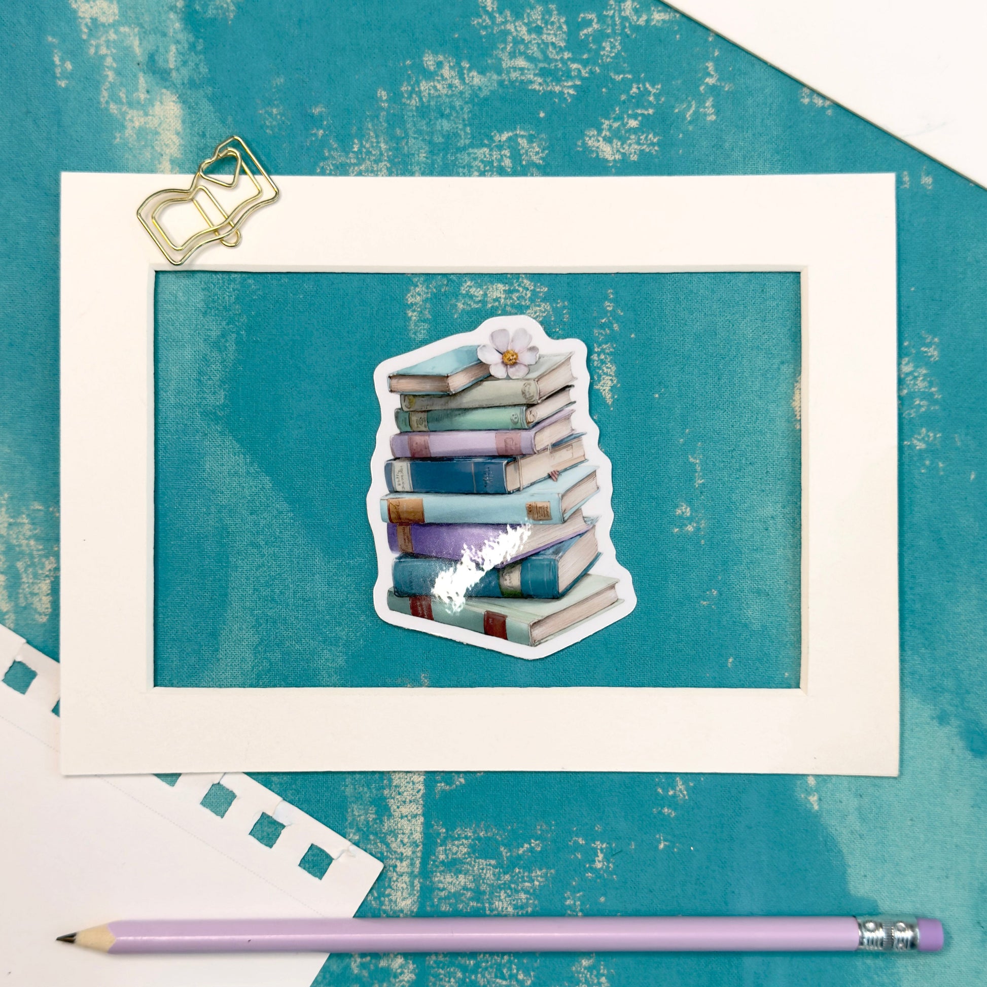 Stack of books sticker on a textured blue background with two pencils below.